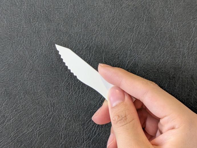 親指と中指で紙ナイフをつまみ、人差し指をナイフの背に添える